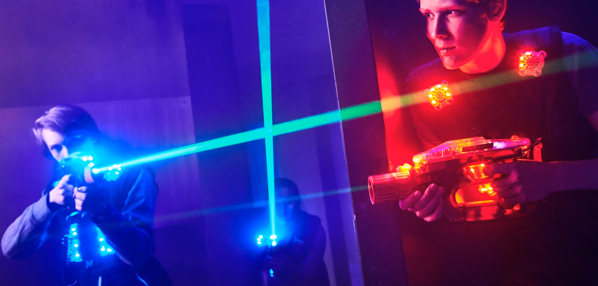 Players taking aim through crossing laser beams in the laser tag arena.