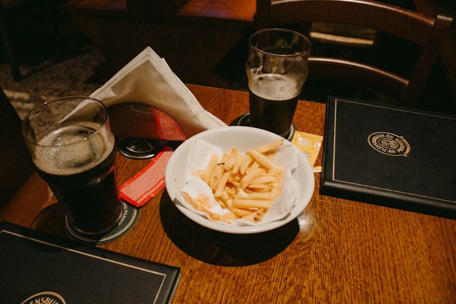 A pint and a bowl of chips on a dark pub table.