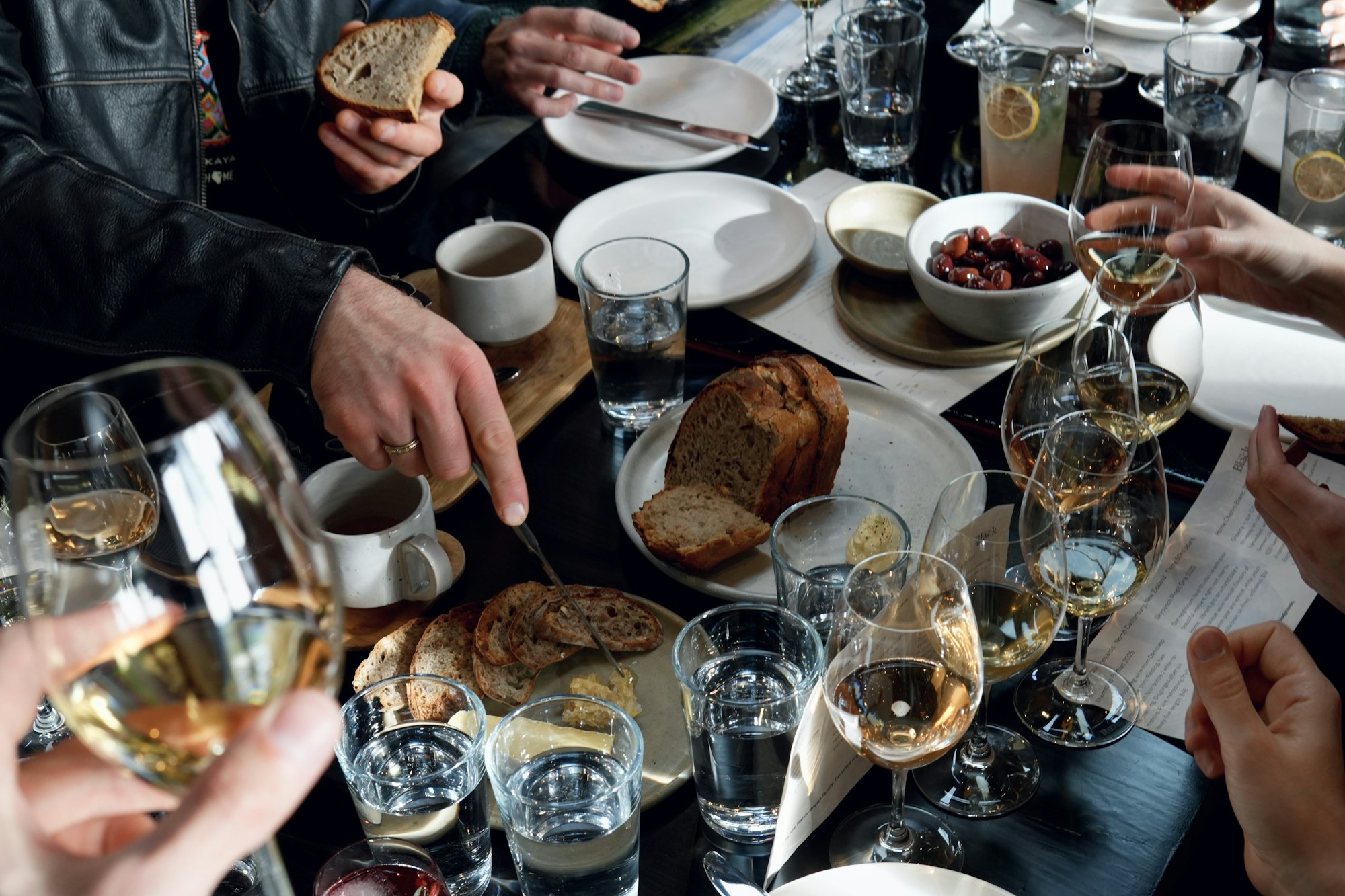 Friends around a table sharing plates of food and glasses of wine.